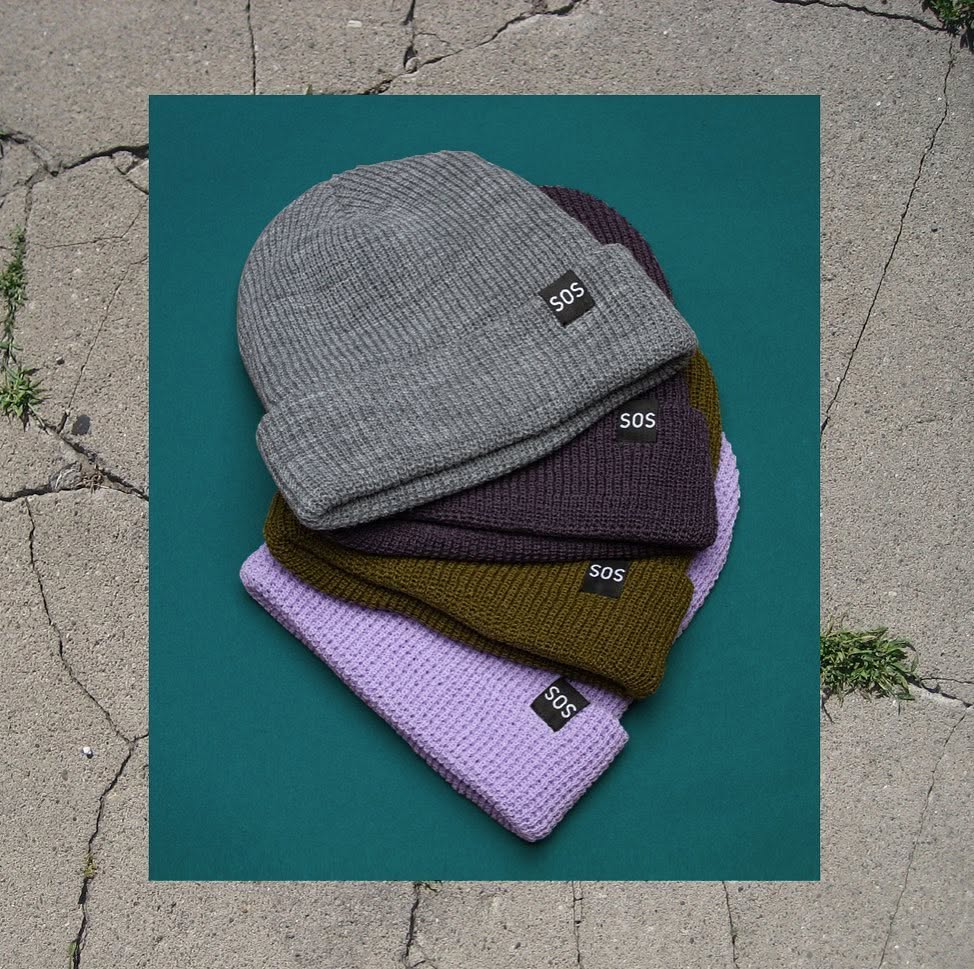 Stack of SOS knit beanies in several colors