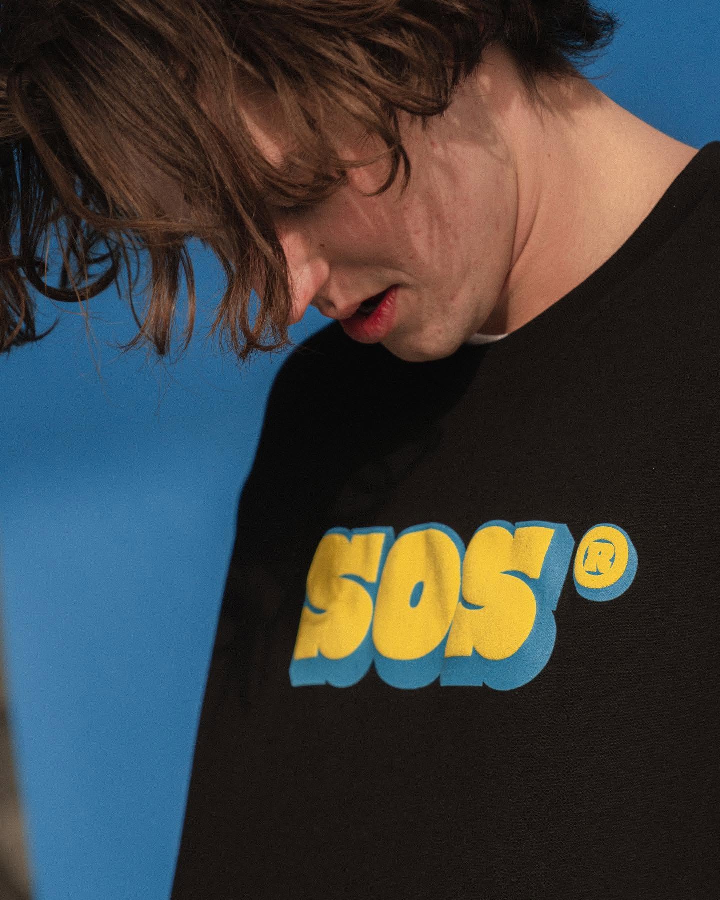 Closeup of a model wearing a retro SOS logo shirt